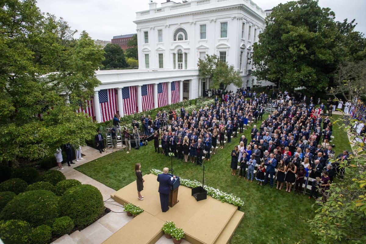 Yhdysvaltain presidentti Donald Trump puhuu tiiviisti istuvalle ihmisjoukolle Valkoisen talon pihalla.