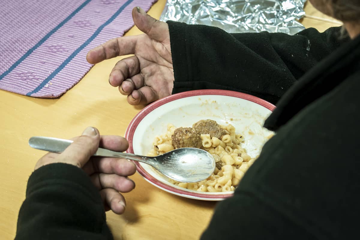 Likaiset kädet ja lautasella makaroonia ja lihapullia.