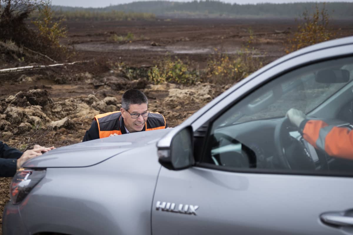 Hannu Hautala työntää turvesuohon juuttunutta autoa.