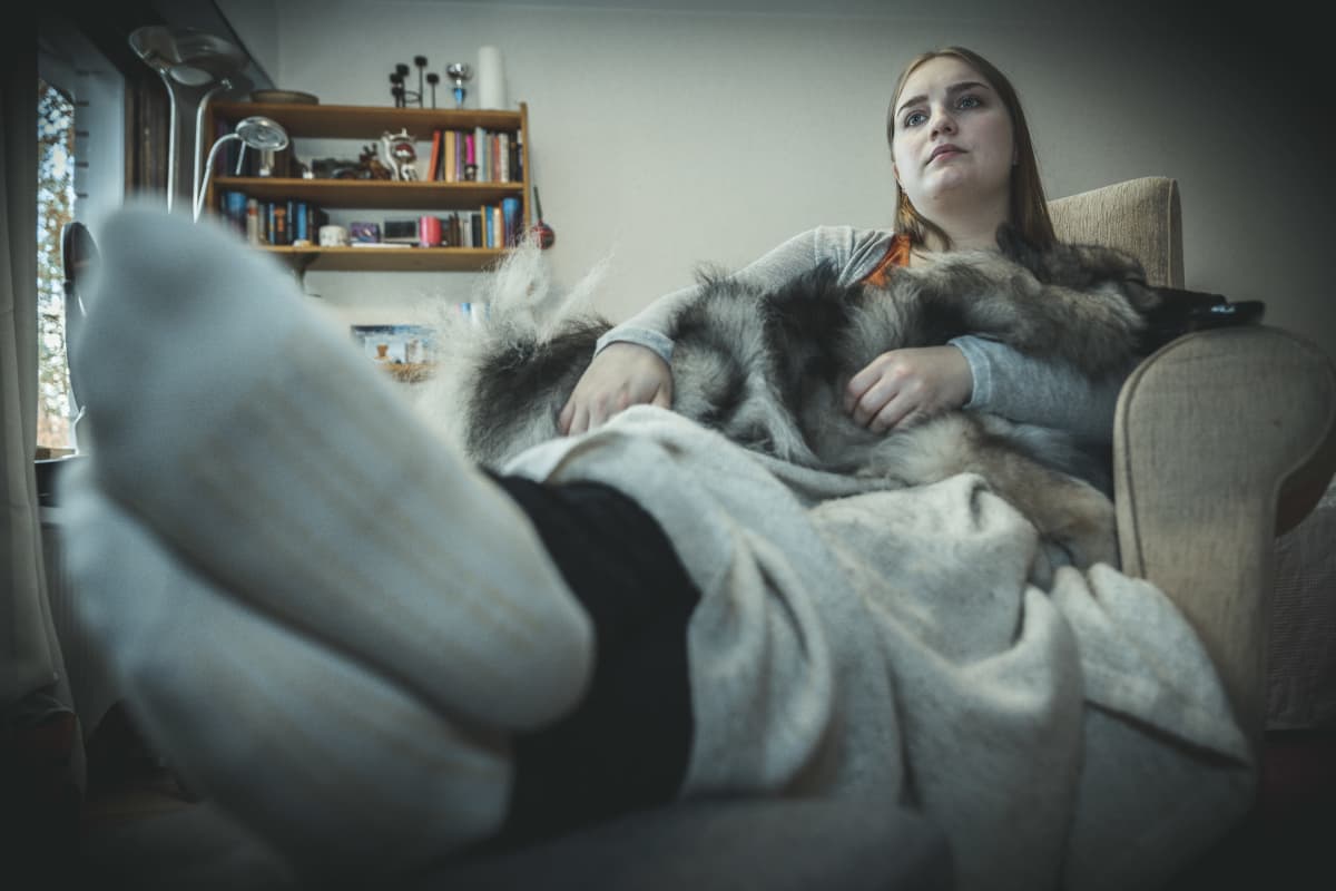 Petra Suonperä koira sylissään katsoo sohvalla kauhuelokuvaa.