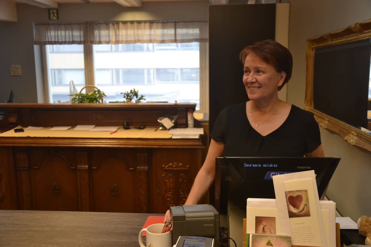 Hyvinvointicenterin johtaja Mirja Lamberg tiskin takana odottamassa asiakkaita.