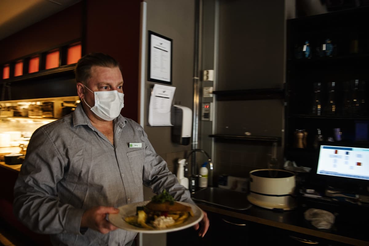 Kuvassa kasvomaskia käyttävä tarjoilija työskentelee ravintola Vltavassa lokakuussa 2020.