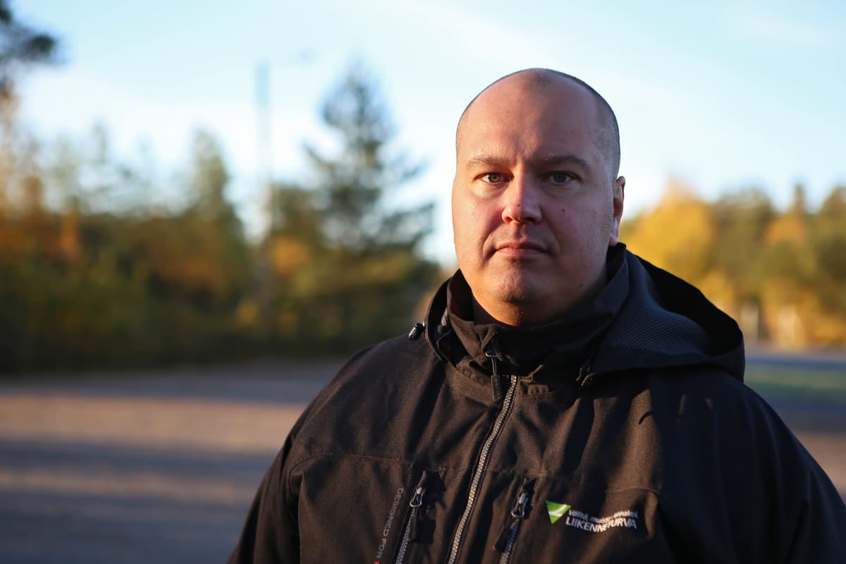 Mies poseeraa kameralle syksyisessä maisemassa.