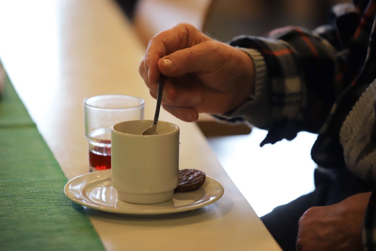 Vanhus sekoittamassa kahvia Jaalan palvelukeskuksessa.