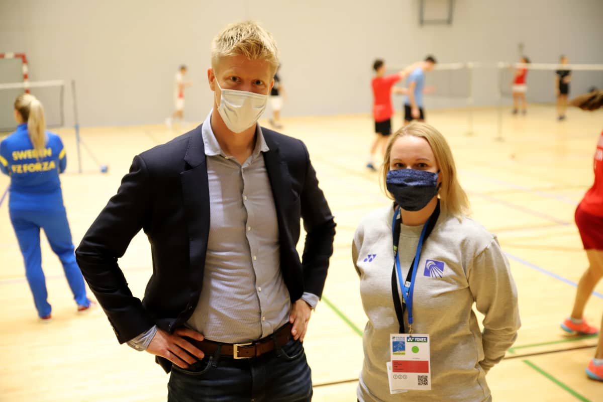 Tero Kuorikoski ja Laura Kittelä kasvomaskit yllään kameraan katsoen sulkapallohallissa