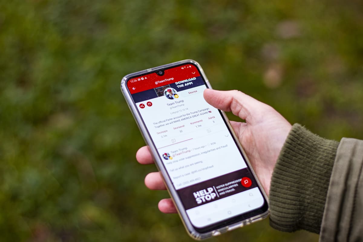 Käsi pitelee puhelinta, jossa on auki sosiaalisen median Parler-applikaatio.
