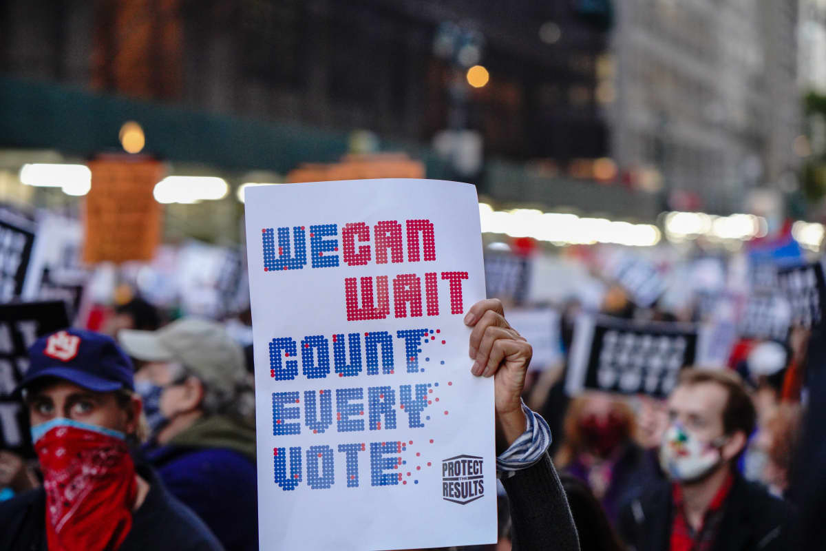 Mielenosoittaja kantaa kylttiä New Yorkissa. Plakaattiin on kirjoitettu englanniksi: We can wait. Count every vote.
