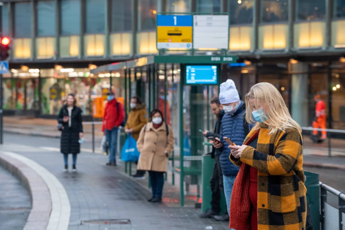 Ihmiset raitiovaunupysäkillä.