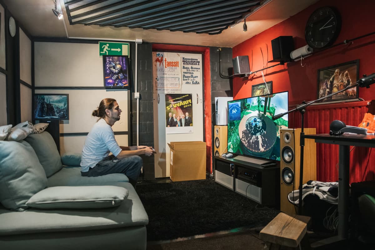 Niko Hyttinen istuu pelihuoneensa sohvalla ja pelaa uudella Playstation 5 pelikonsolilla.