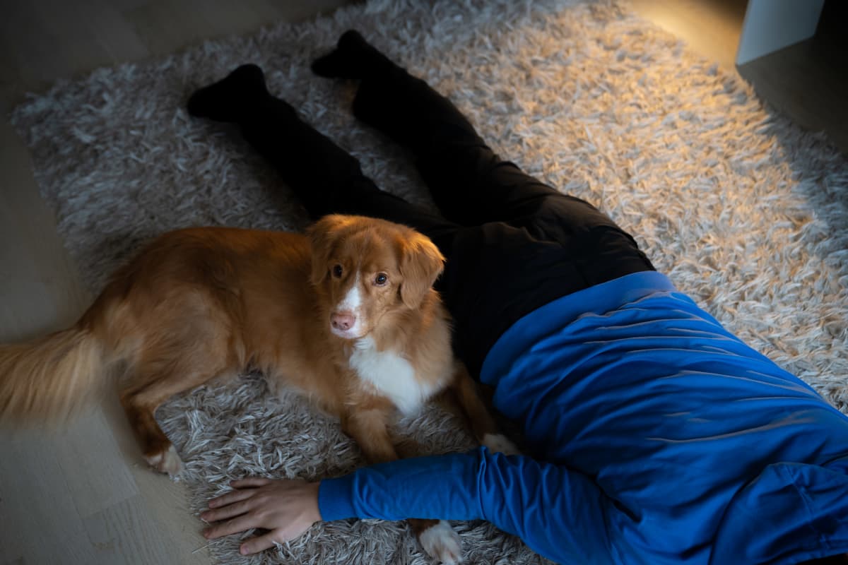 Mikko Vikman makoilee lattialla koiransa kanssa.