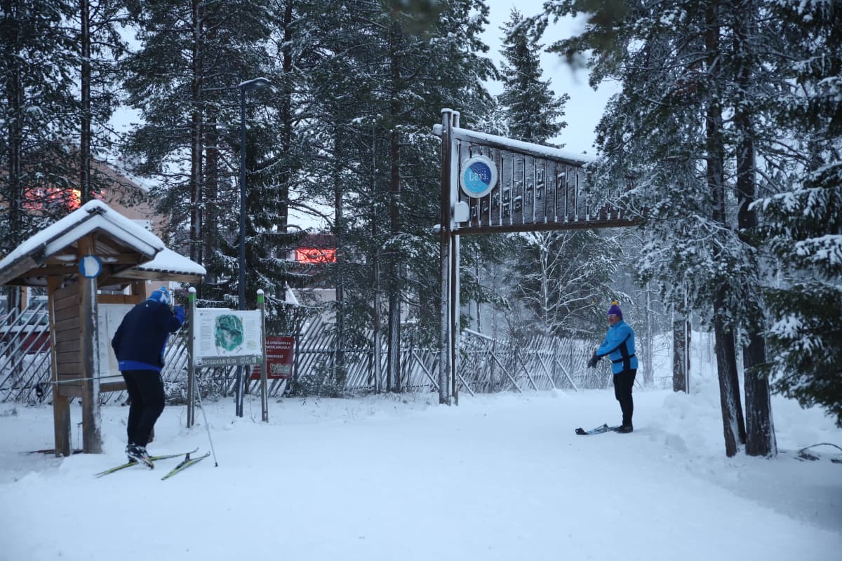 Hiihtoladulle lähtijöitä ja tulijoita talvisessa maisemassa