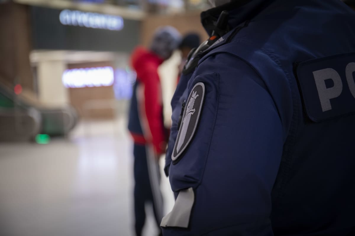 Poliisin hihamerkki, taustalla nuorehkoja henkilöitä.