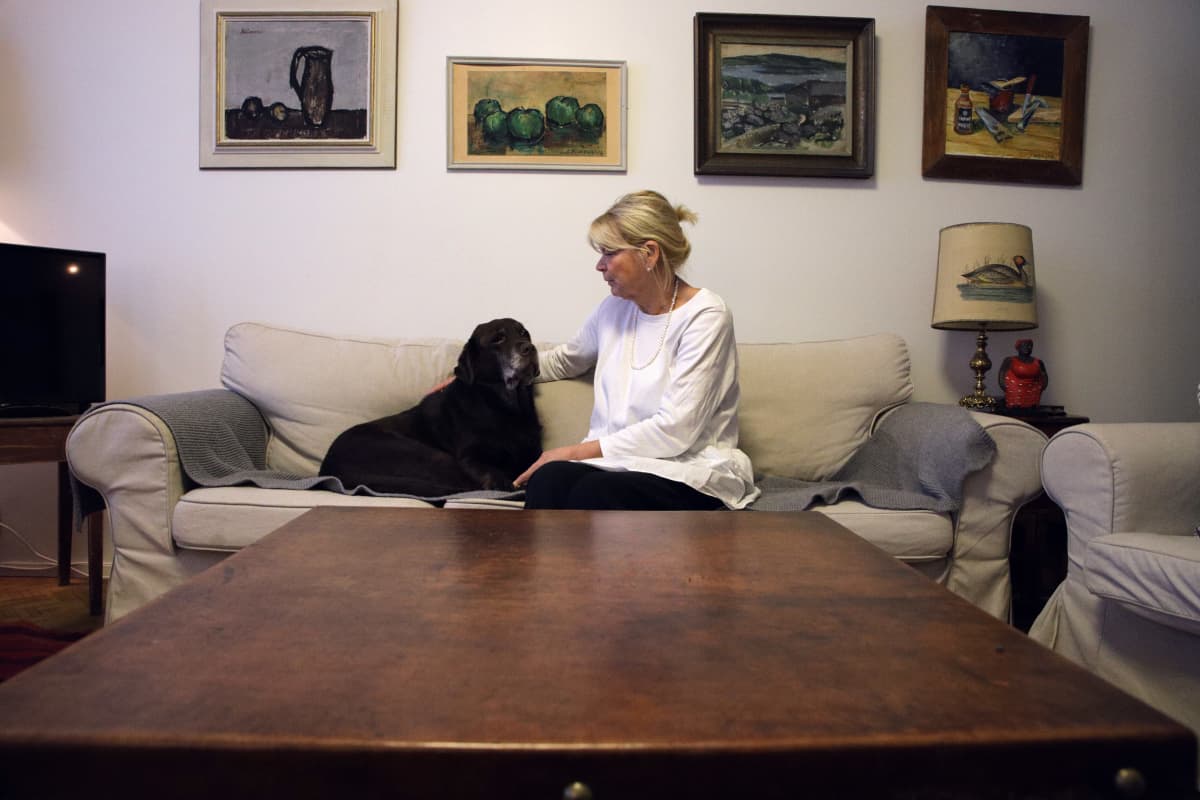 Jessica Löfgren-Eriksson istuu Luna-labrdorinnoutajansa kanssa sohvalla.