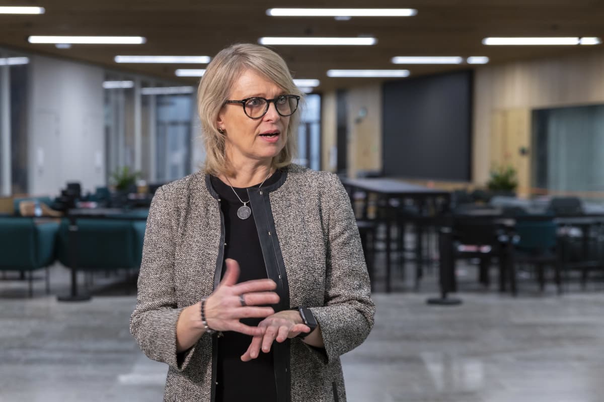 Aalto-yliopiston kauppakorkeakoulun professori Virpi Tuunainen seisoo yliopiston autiossa kahvilassa ja selostaa käsien kera asiaansa haastattelijalle, jota ei näy kuvassa.