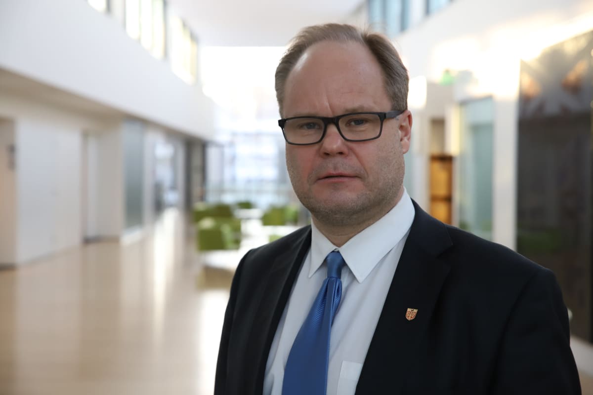 Mies puku päällä katsoo kameraan
