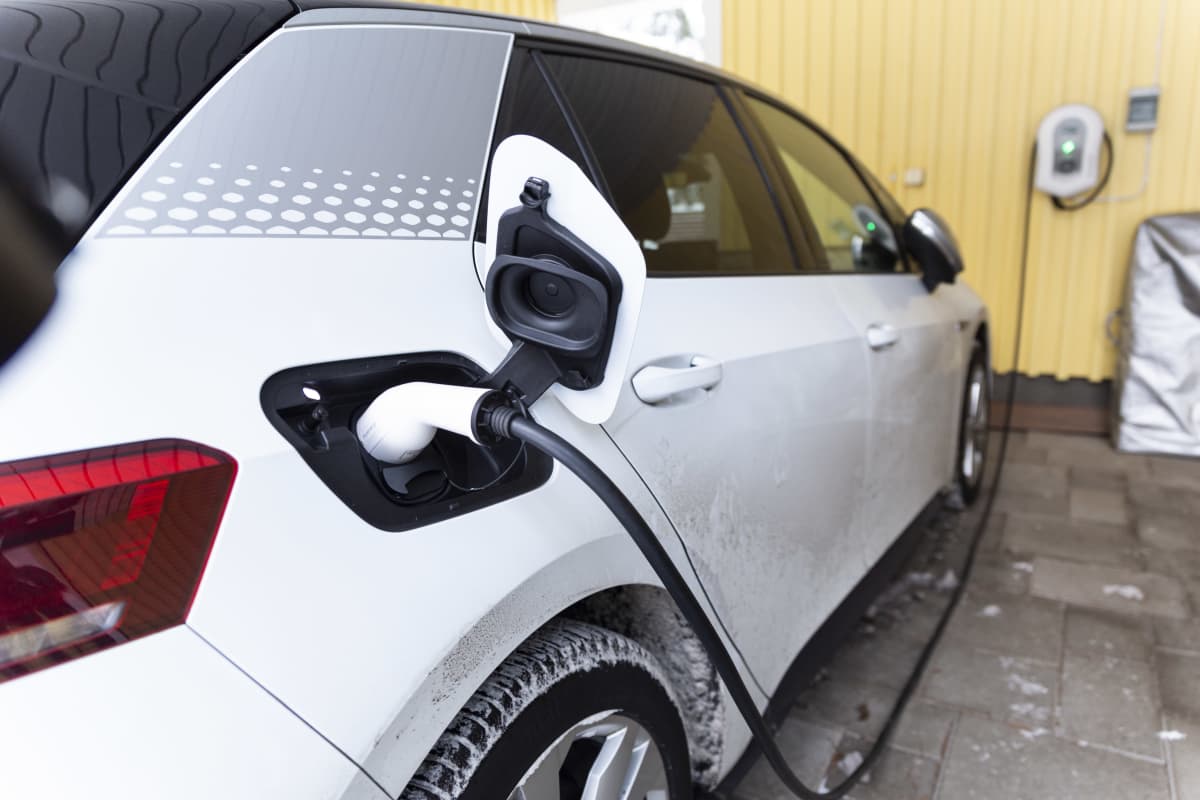 Sähköauto latauksessa omakotitalon autokatoksessa.