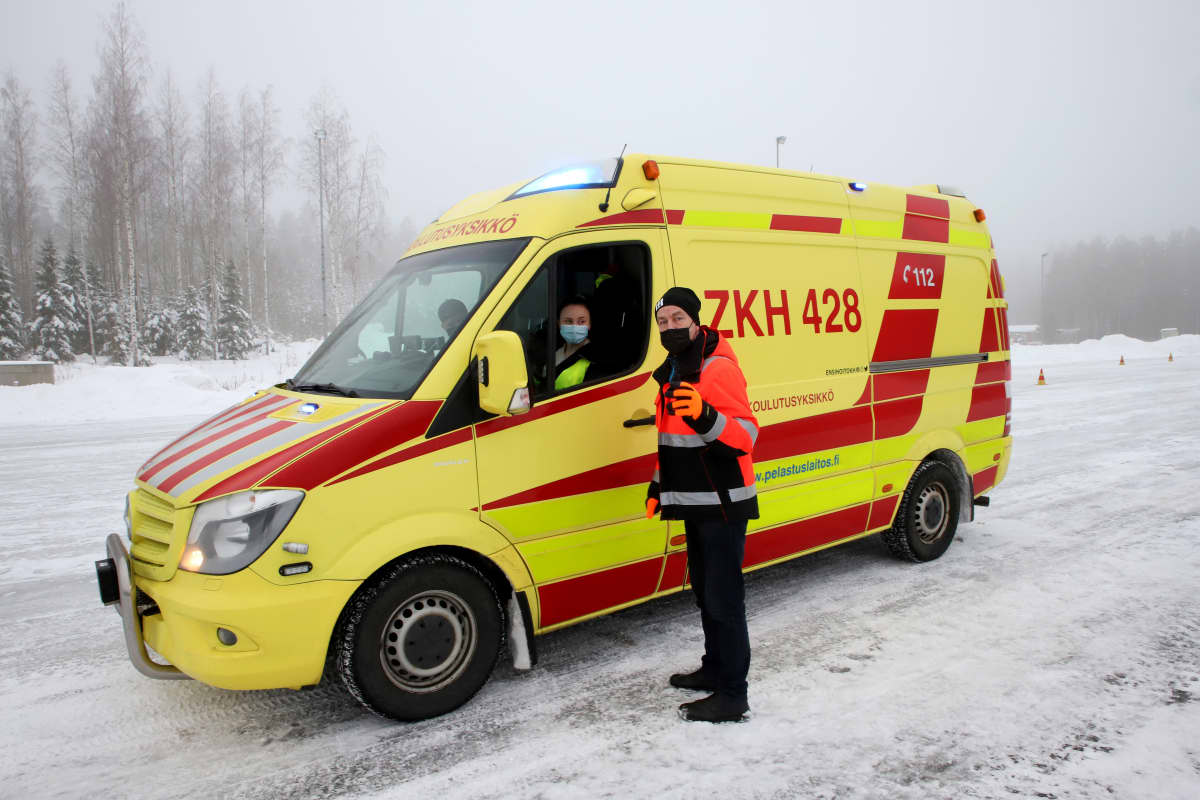 Lehtori Olli Seppälä ambulanssin edessä antamassa neuvoja auton ratissa olevalle ensihoidon opiskelijalle.