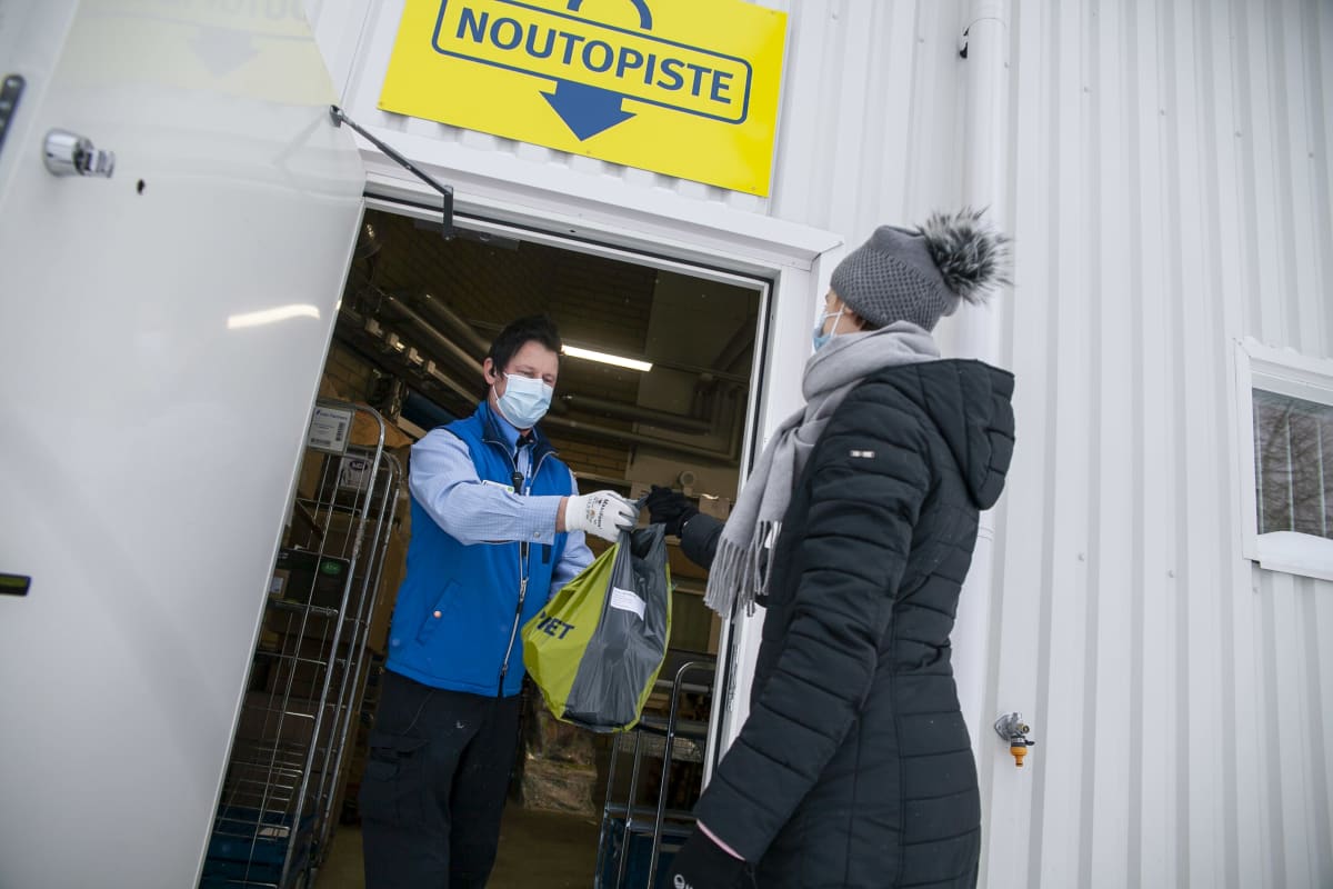 Petri Taattola ojentaa verkokauppa -tilauksen Kaisa Ilvoselle kaupan takaovella