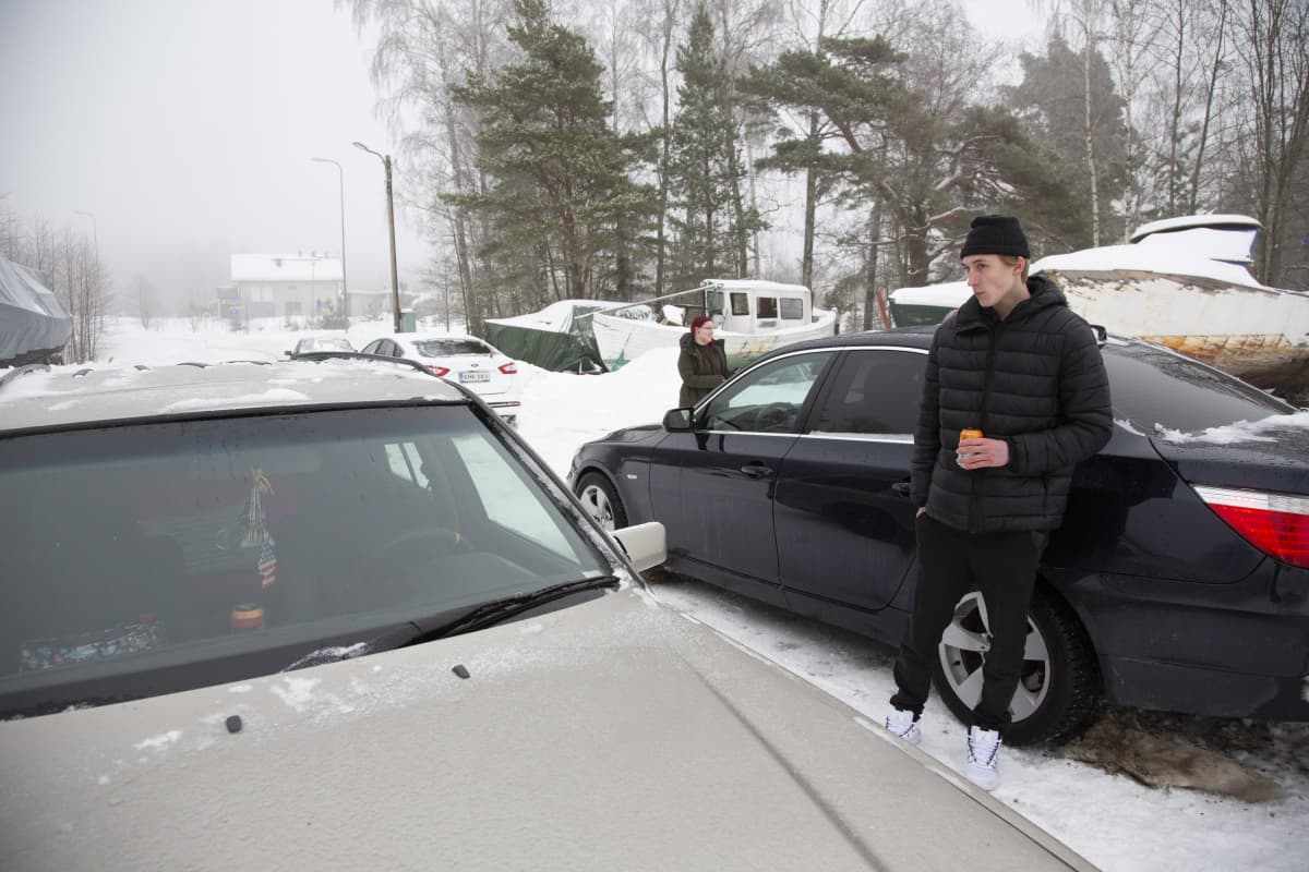 Tatu Kotiranta nojaa autoon. Taustalla Nea Nyholm.
