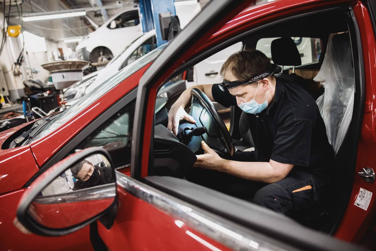 Alppilan autohuollon mekaanikko Jari Kopra laittaa auton osia takaisin paikoilleen etähallintalaitteen asennuksen jälkeen.