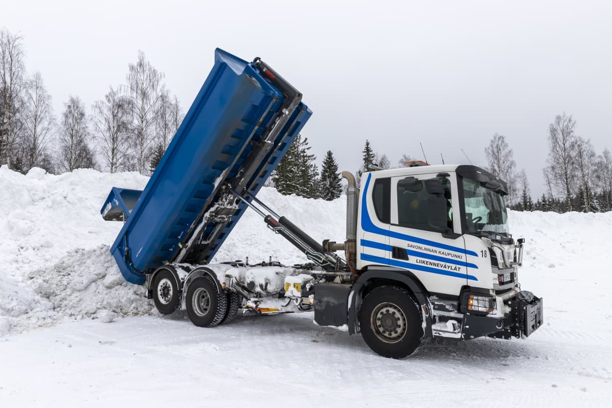 Kuorma-auto kaataa lunta kasaan Viitasuon lumenkaatopaikalla.