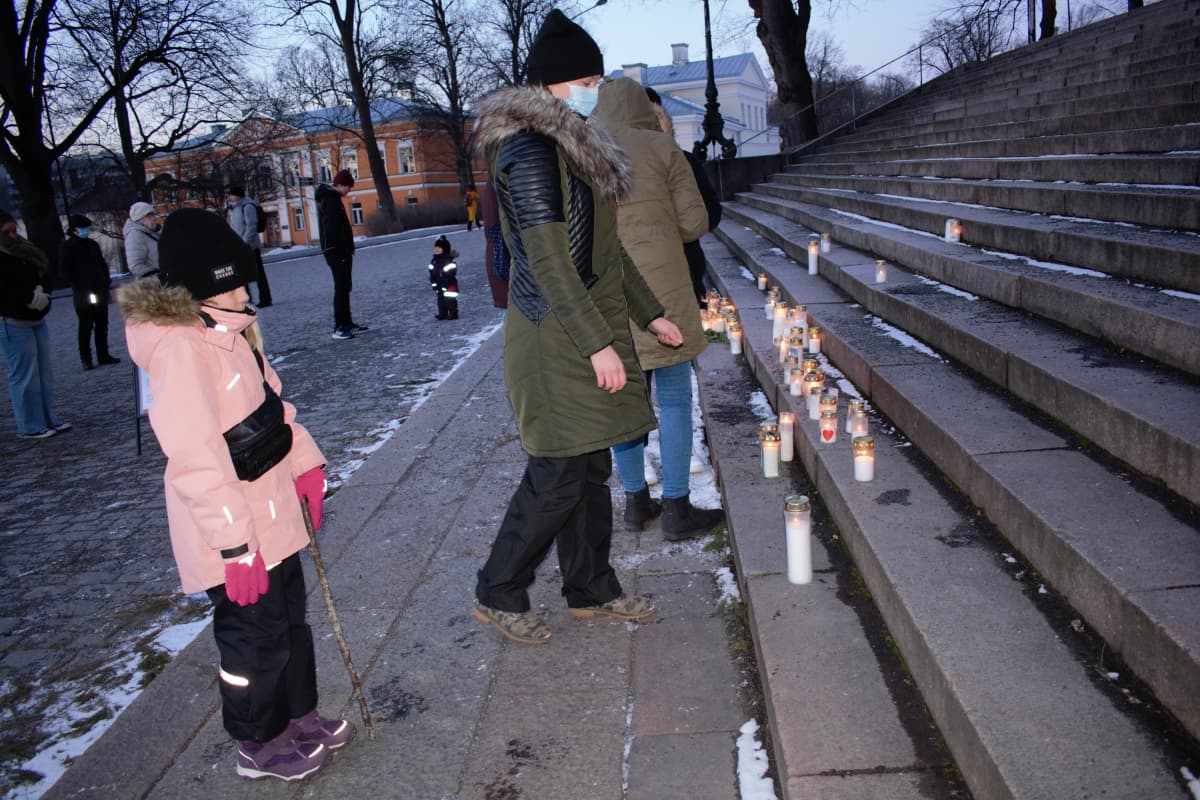 Äti ja tytär jättämässä muistokynttilää Turun tuomikirkolla 5.3.2021.