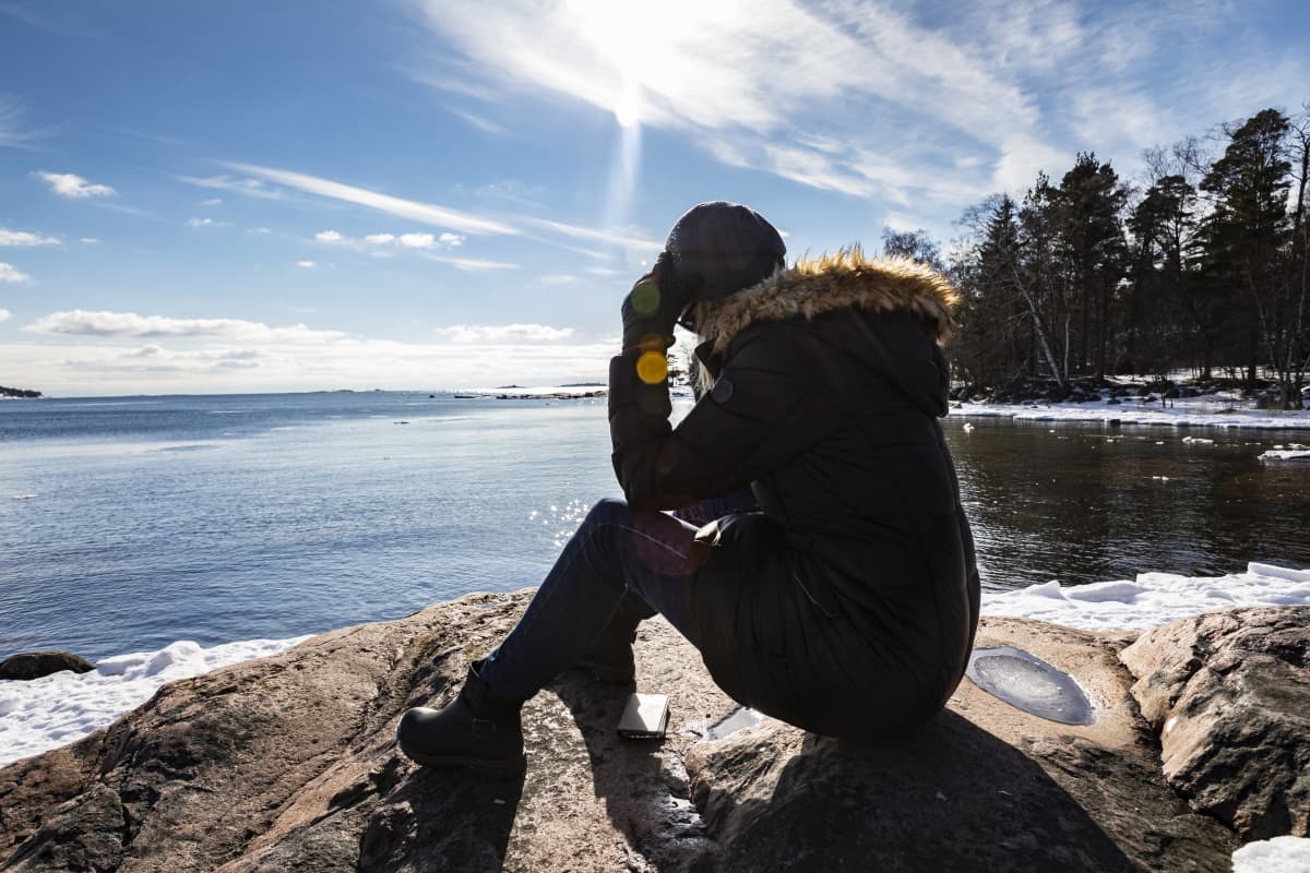 nainen istuu kalliolla