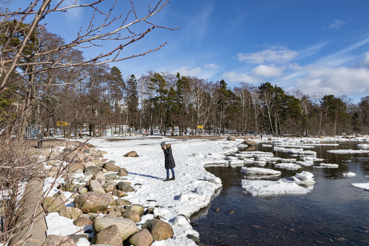 nainen puhuu puhelimeen rannalla