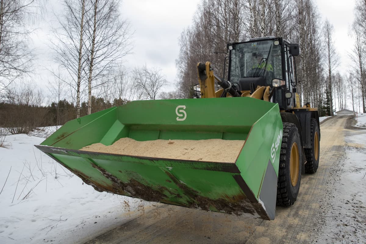 Koneenkuljettaja Santeri Tolppanen kuljettaa traktoria, jonka kauhassa on liukkaudentorjuntaan tarkoitettua sahanpurua.