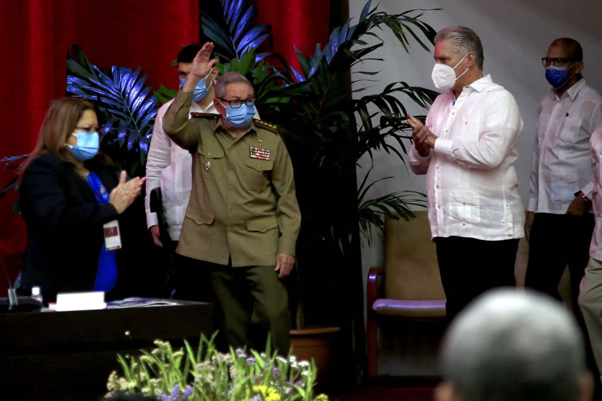 Miguel Diaz-Canel taputtaa, kun Raul Castro vilkuttaa yleisölle lavalla.