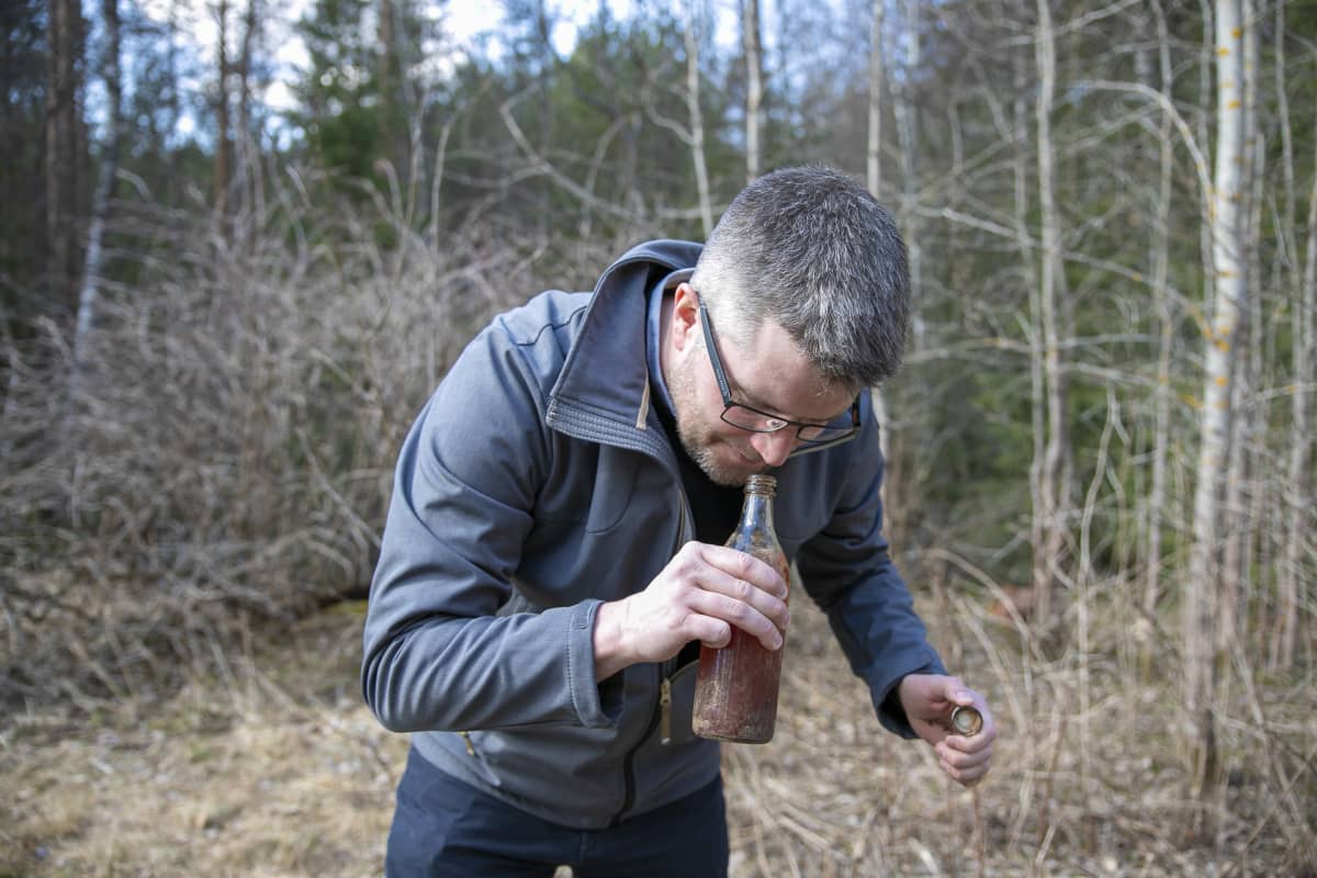 Mikko Keränen haistaa löytyneen pullon sisältöä.