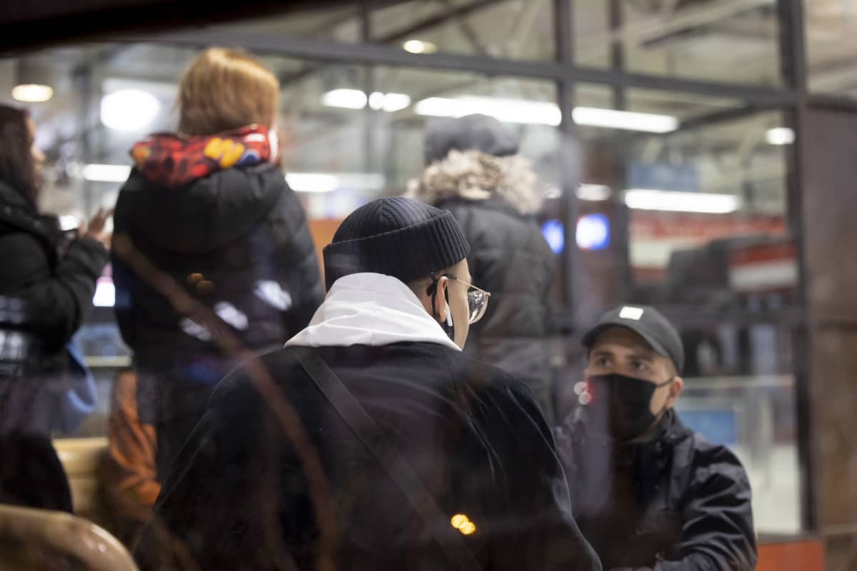 toimittaja haastattelee nuorta miestä, taustalla seisoo kolme tyttöä
