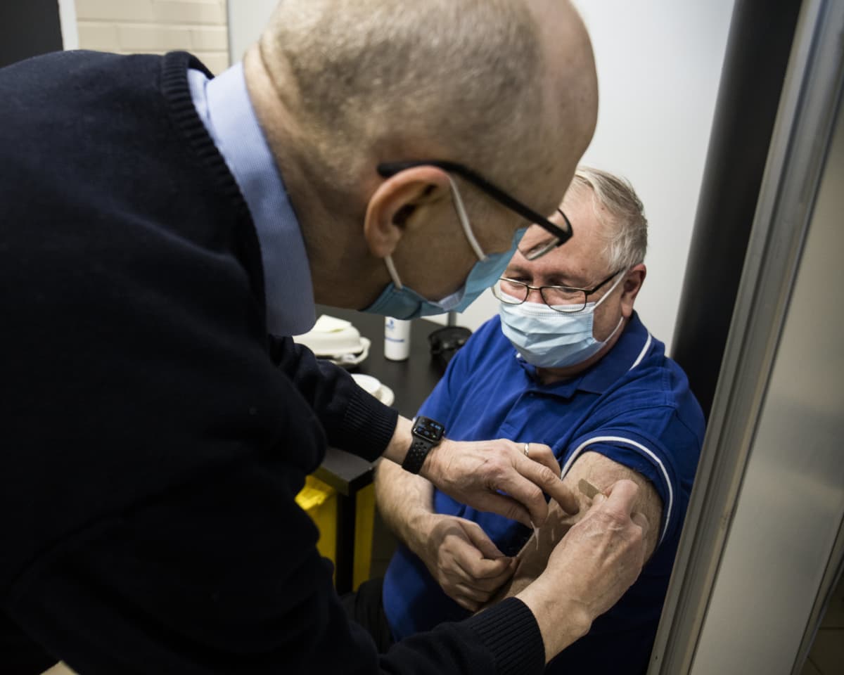 Vapaaehtoinen rokottaja Juha Metso antaa koronarokotteen Ilkka Virtaselle.