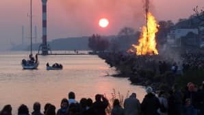 Suuri kokko ja paljon ihmisiä joen varrella.
