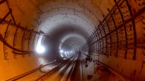 Metrotunneli on rakenteilla Moskovassa. Punaista ja siniharmaata valoa heijastuu tunnelin seinälle.