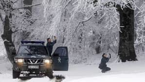 Kaksi poliisia kuvaa kännyköillään lumista maisemaa.