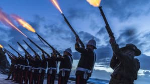 Rivi historiallisesti pukeutuneita sotilaita ampuu ilmaan,