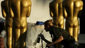 Nainen suihkumaalaa isoja Oscar patsaita.