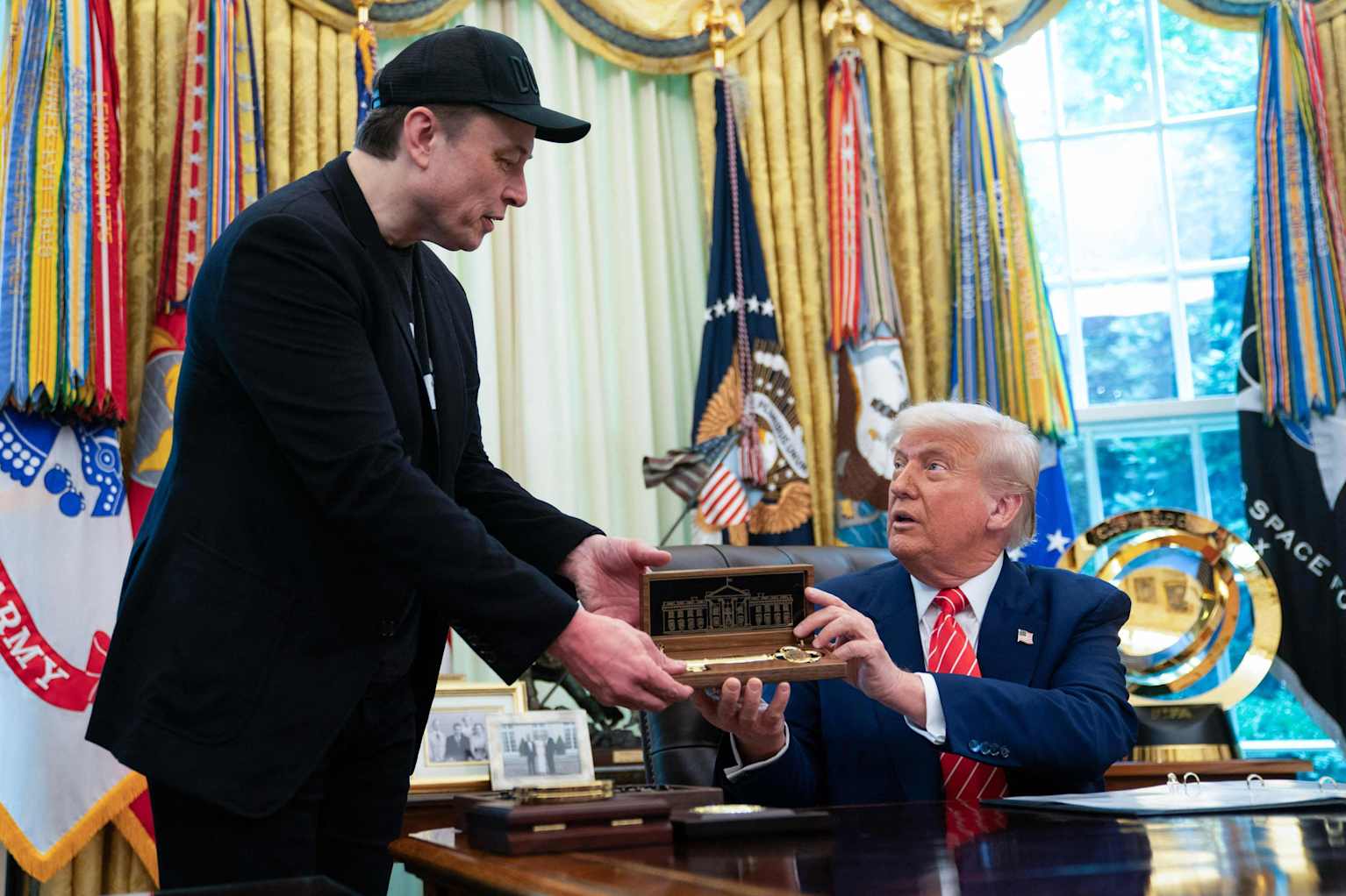 President⁤ Trump hands Elon​ Musk a golden key at a⁢ White House press conference.