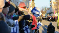 Kuva väkijoukosta katsomassa paraatia käsissään suomenlippuja.