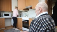 Lähihoitaja tiskaa kotona, 95 vuotias veteraani istuu keittiössä.
