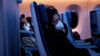 Hengityssuojin varustautuneita matkustajia lentokoneessa.