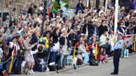 Ihmiset heiluttavat Ruotsin lippujen kadun varrella Tukholmassa.