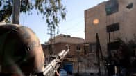 Syyrian armeijan sotilas tähystää rynnäkkökiväärillä matalaa kerrostaloa.