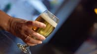 Glass of beer held in a woman's hand.