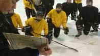 Nuoret jääkiekkoilijat kuuntelevat valmentajaa