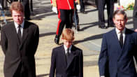 Harry kävelee miesten keskellä. Kaikki ovat pukeutuneet mustiin.