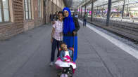 Nainen kahden lapsen kanssa Helsingin rautatieasemalla. 