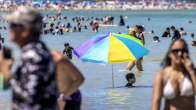 Rantailija käyttää aurinkovarjoa peittääkseen itsensä modernin historian kuumimman kesän aikana Miami Beachissä.