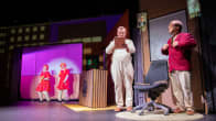Kemin teatterin Fingerpori-näytelmän kohtaus, jossa kaksi miestä etualalla ja kaksi laulavaa naishahmoa taustalla.